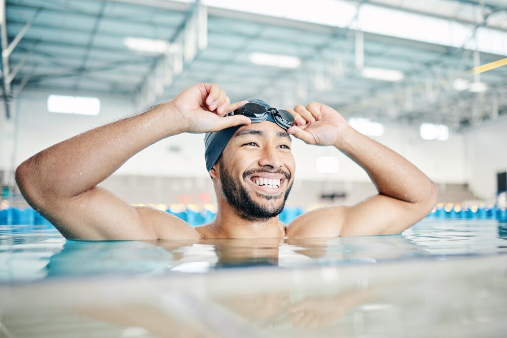Happy, man or relax in swimming pool with cap or goggles in sports wellness, training or exercise i