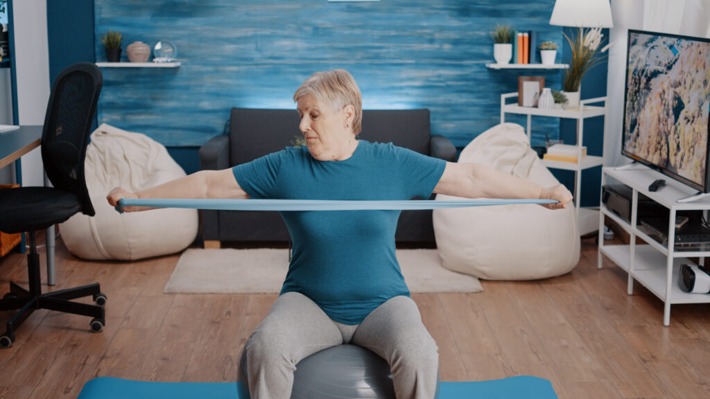 Retired person stretching arms muscles with resistance band