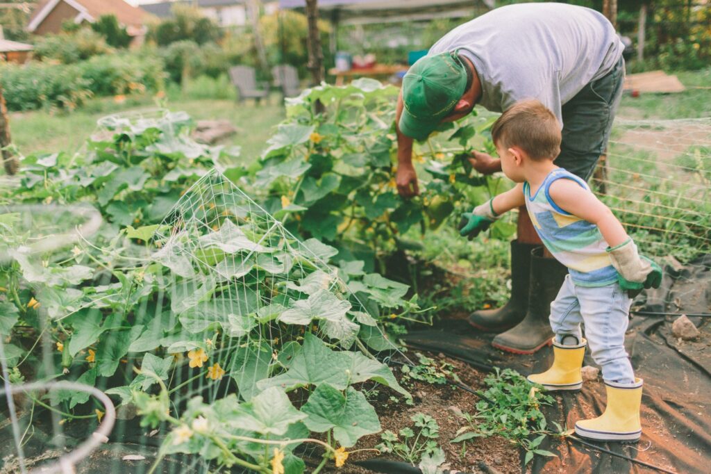A man teaching a little boy how to garden and farm.