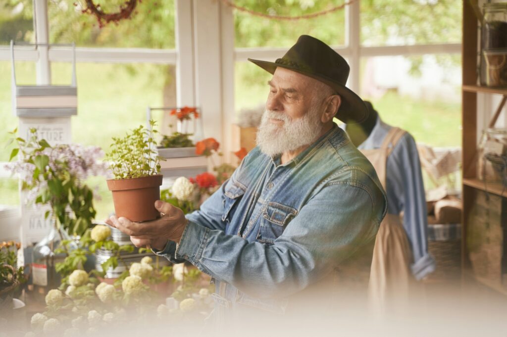 Happy old man enjoying work in own flower shop