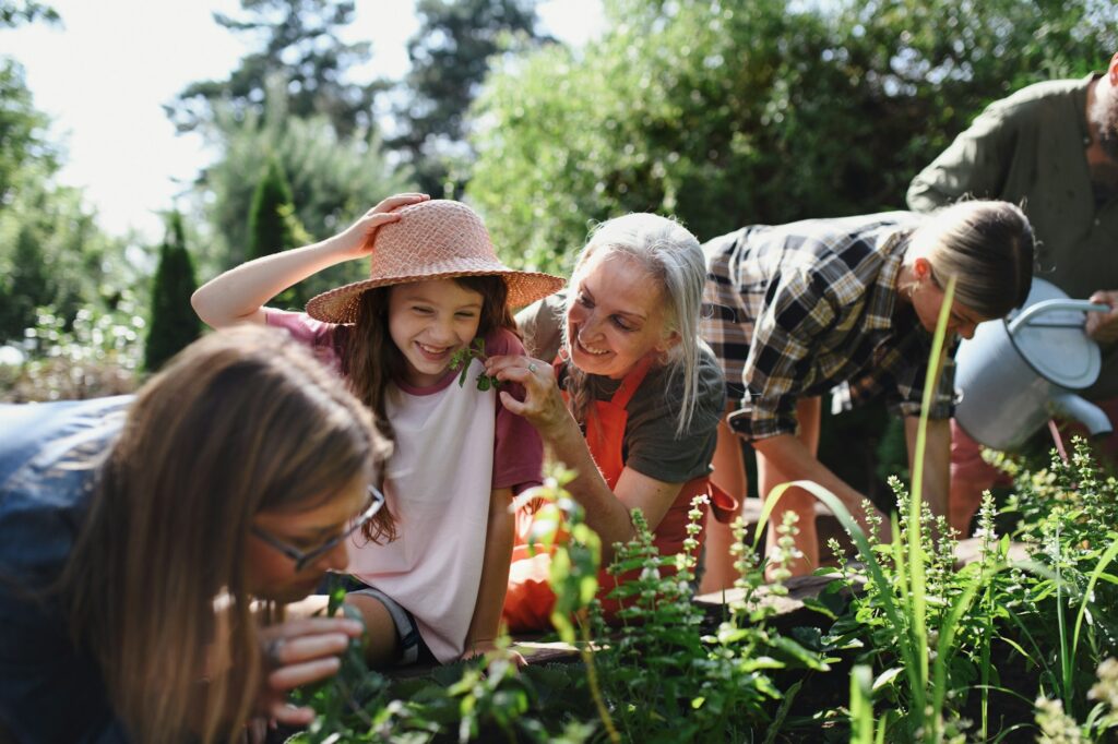 Happy young and old farmers or gardeners working outdoors at community farm