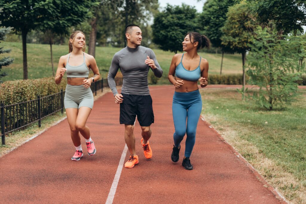 Diverse group of smiling, happy sportswomen and handsome coach wearing stylish sportwear running