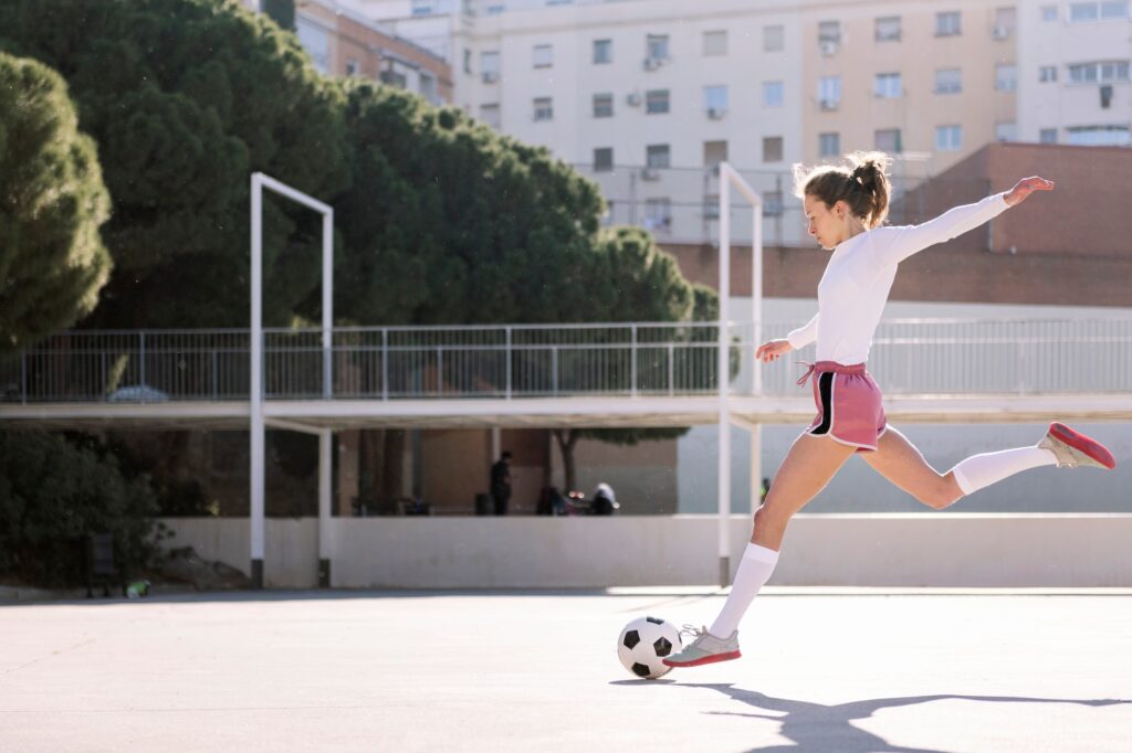 young caucasian woman kicking a soccer ball